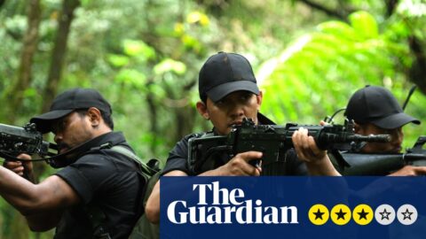 Three men in black tactical gear aim rifles while moving through a dense forest