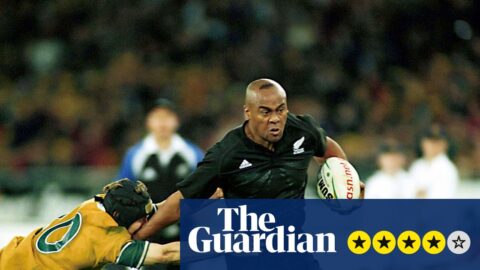 Jonah Lomu carries the ball while evading a tackle attempt from an Australian opponent